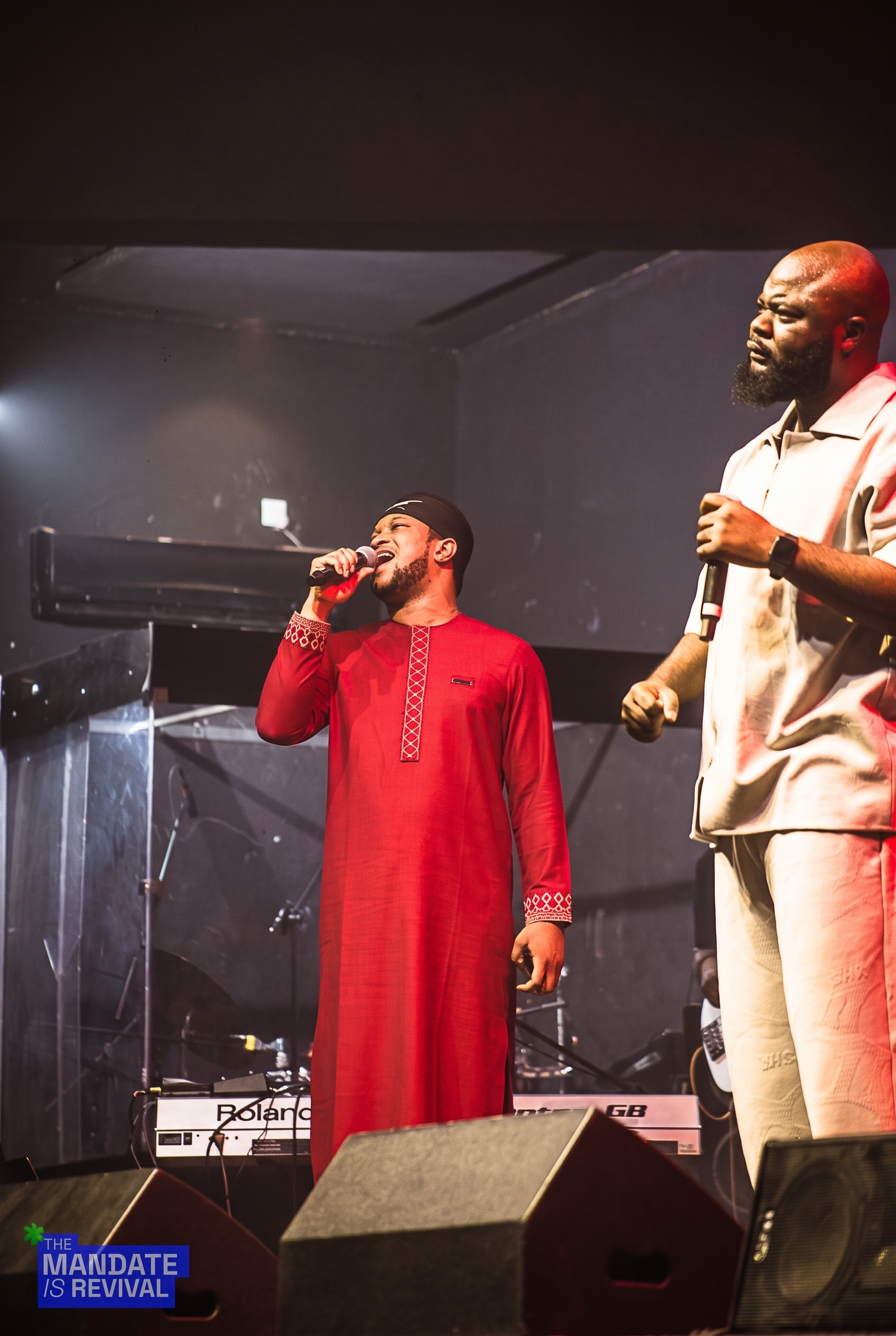 Samuel Folabi on stage beside a singer in a red kaftan