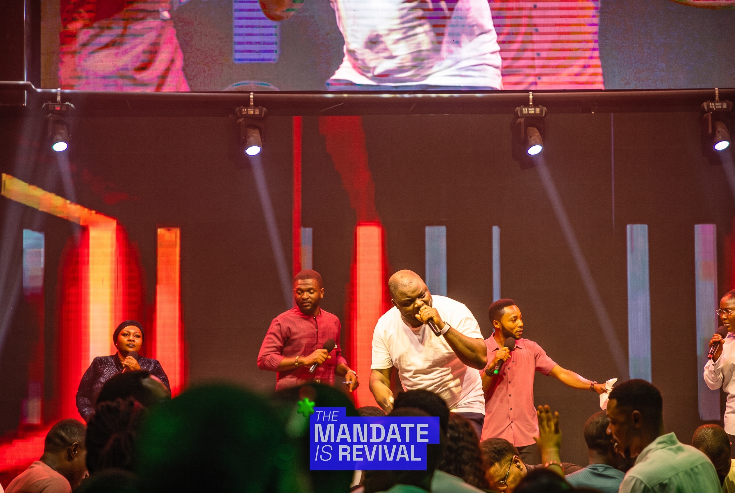 Samuel Folabi ministering intensely with backing vocalists on a red-lit stage