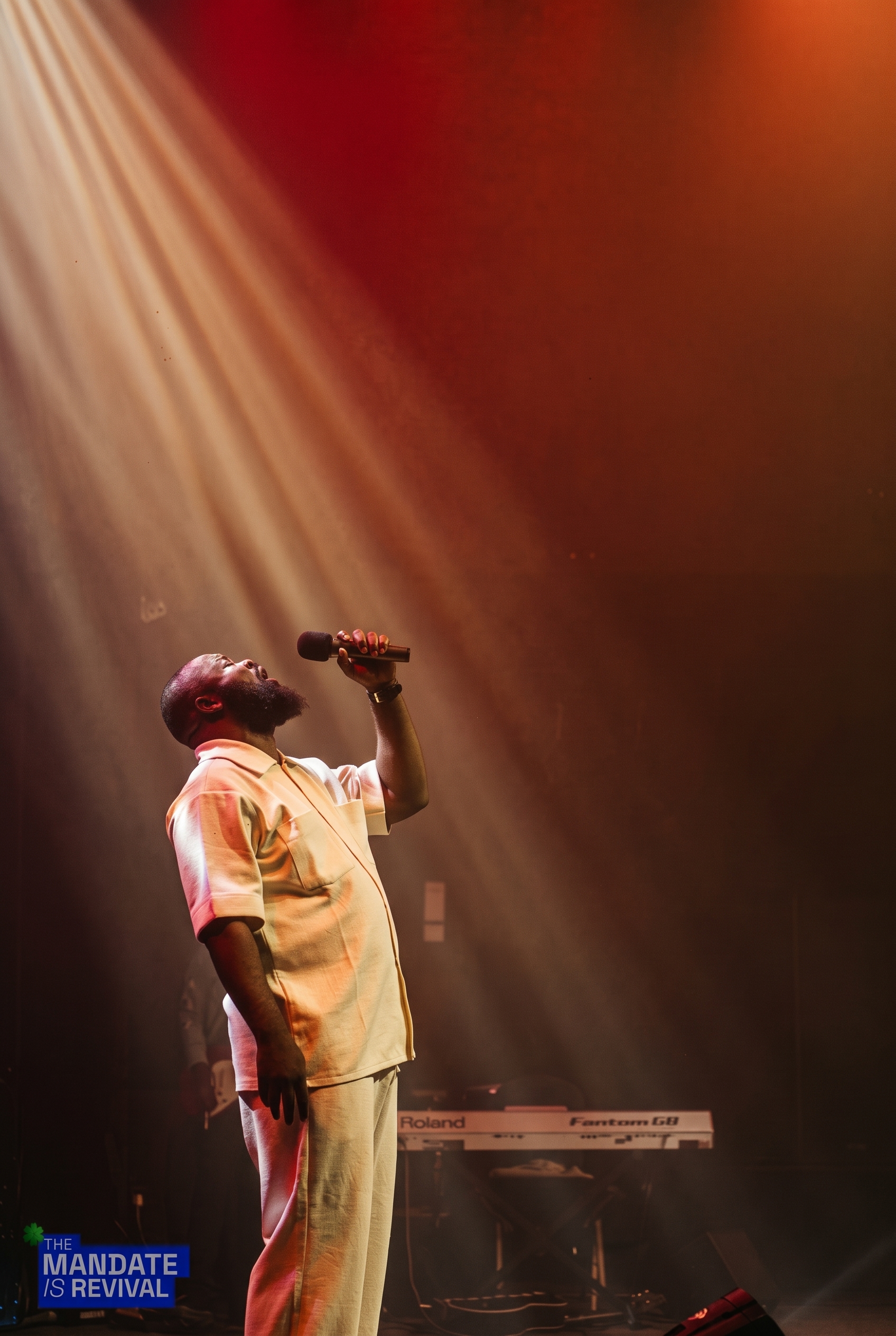Samuel Folabi in white, head lifted toward a warm beam of stage light as he sings
